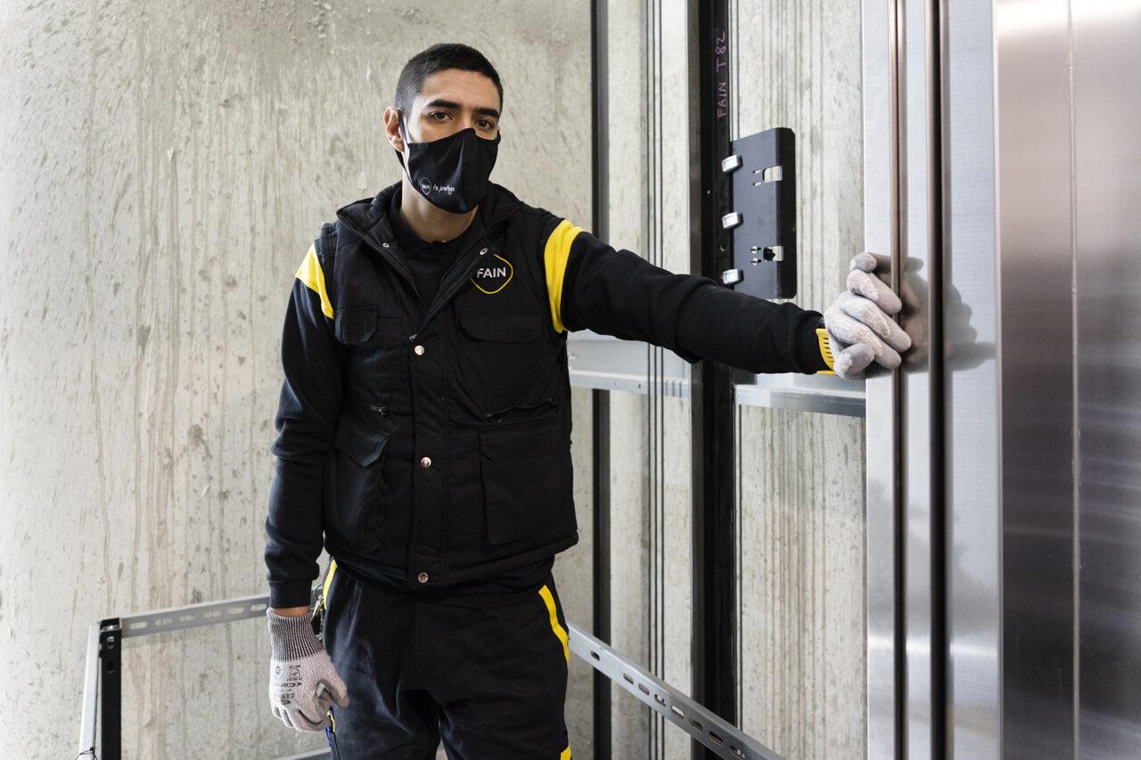 Técnico de FAIN sujetando la puerta de un ascensor