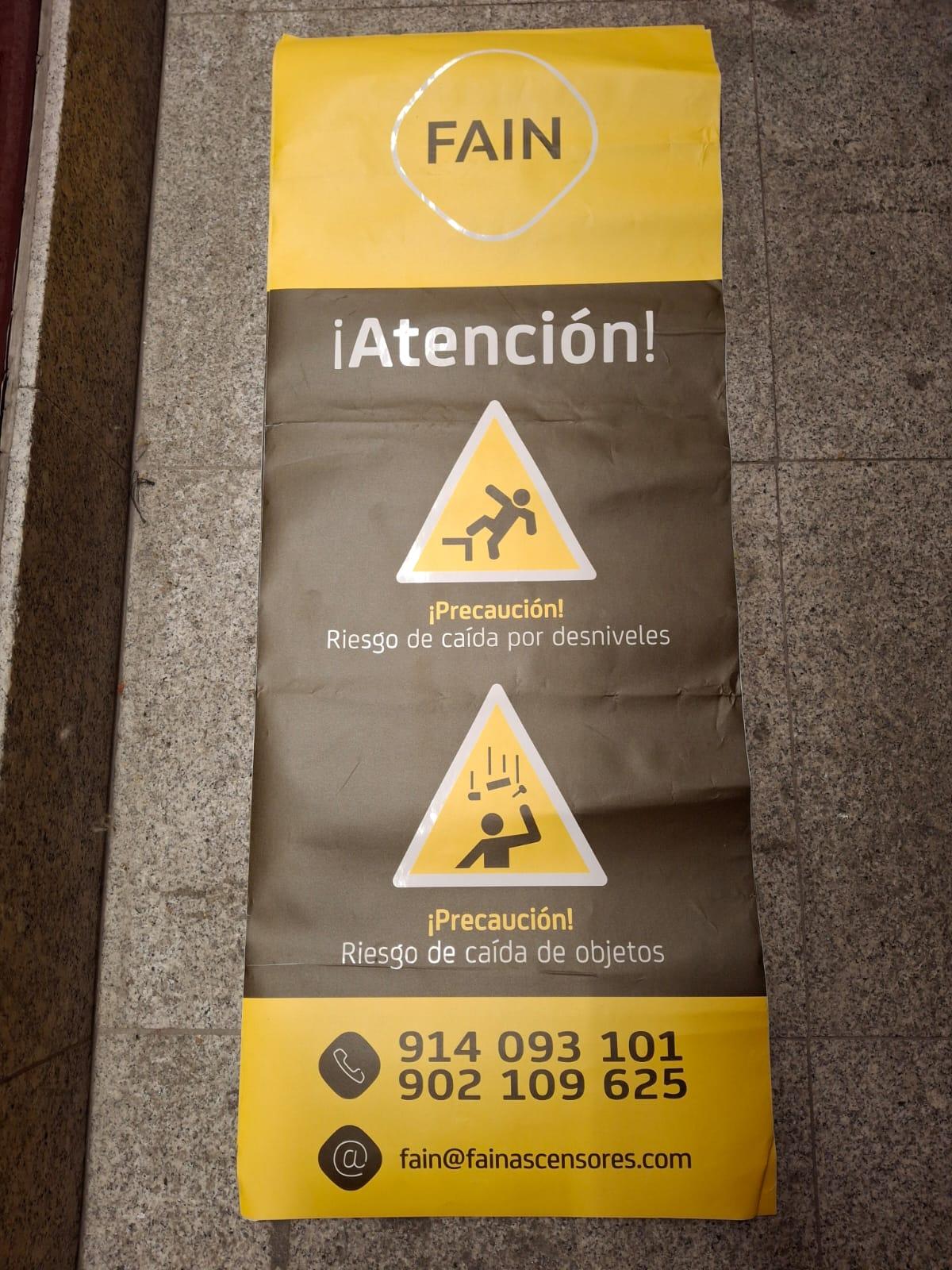 Cartel de aviso de obra en el portal de un edificio