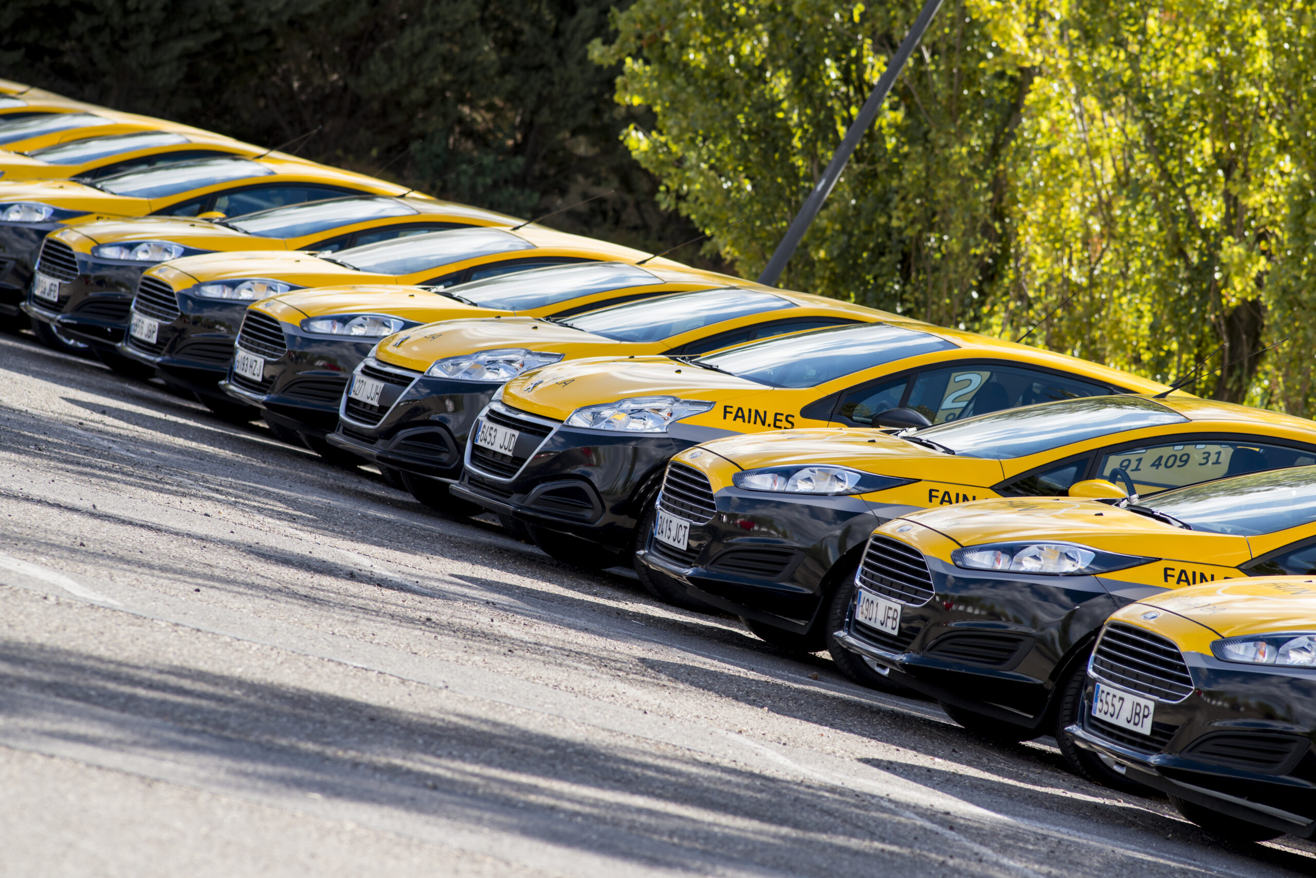 Coches amarillos y negros de la empresa FAIN alineados en fila.
